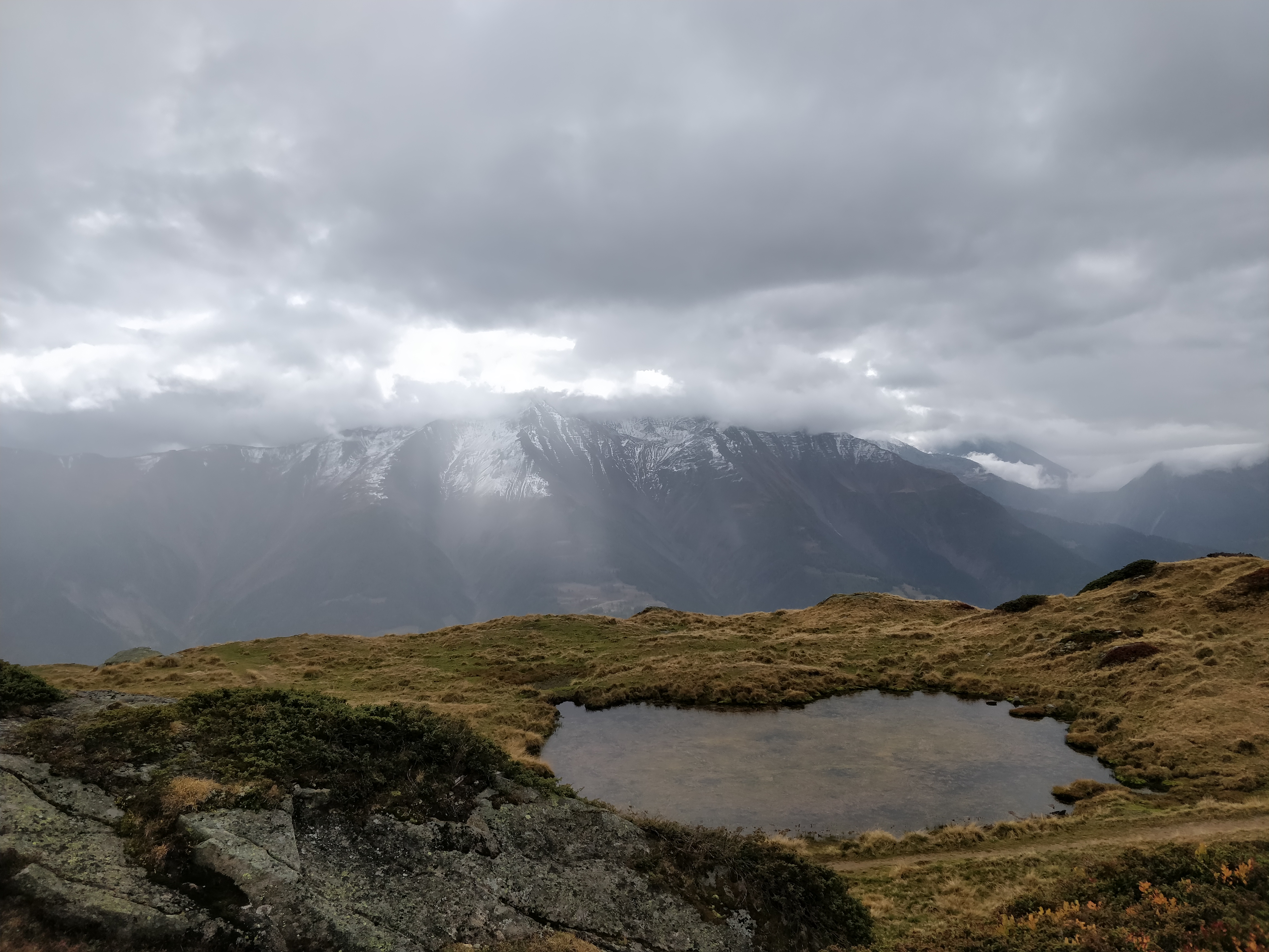 Cloudy mountain view with a peaty pond.